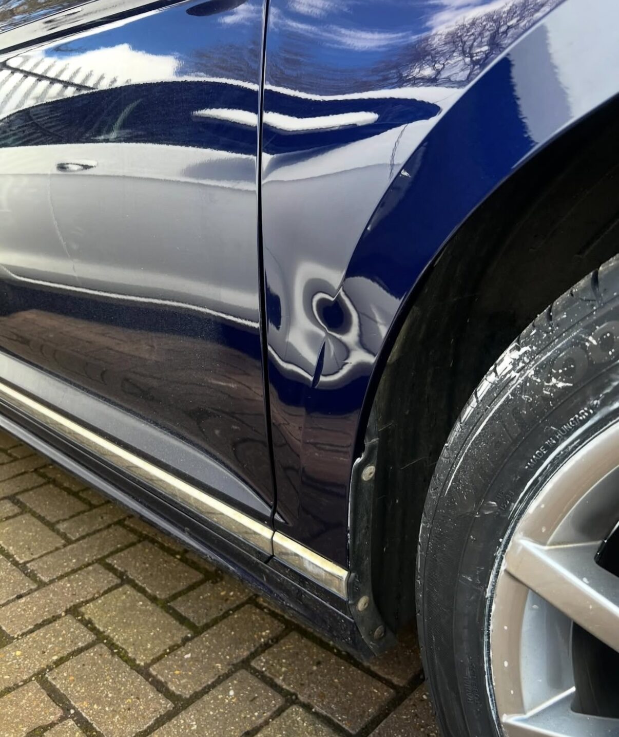 Blechschaden an Tür und Schweller eines blauen Fahrzeugs