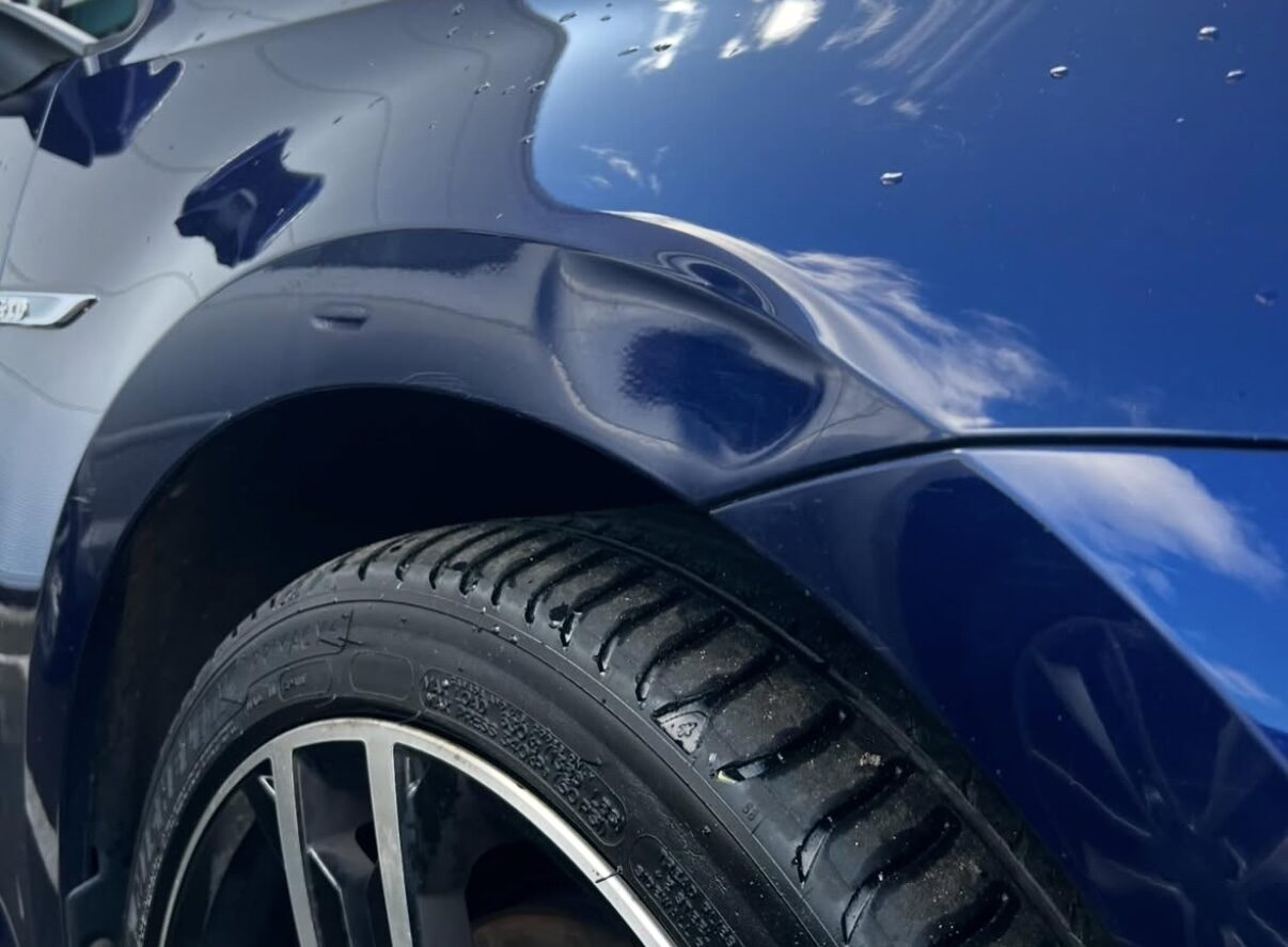 Verformter Kotflügel eines blauen Fahrzeugs