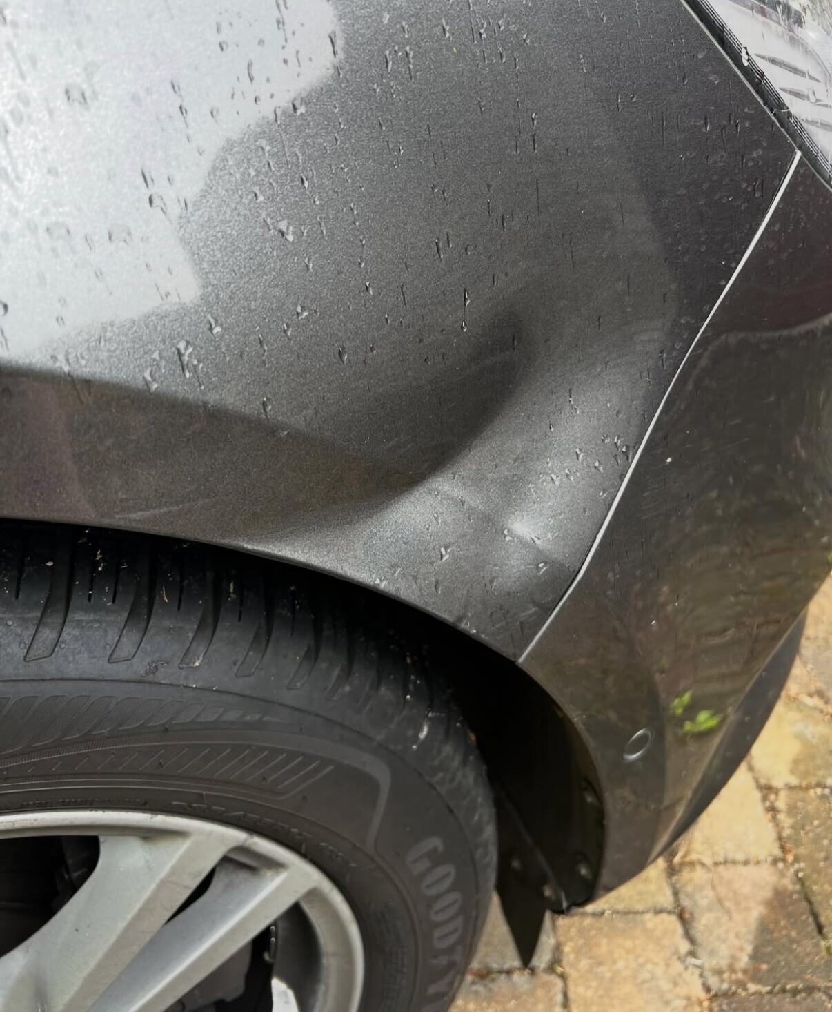 Große Delle im hinteren Kotflügel eines grauen Fahrzeugs